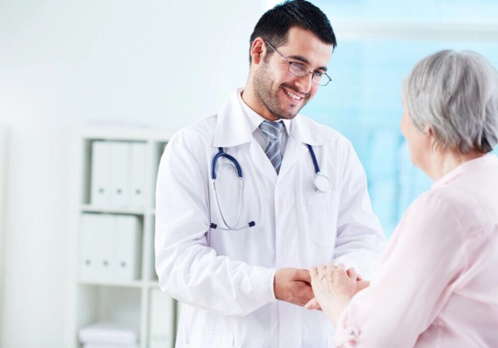 Doctor comforting elderly patient, smiling warmly.