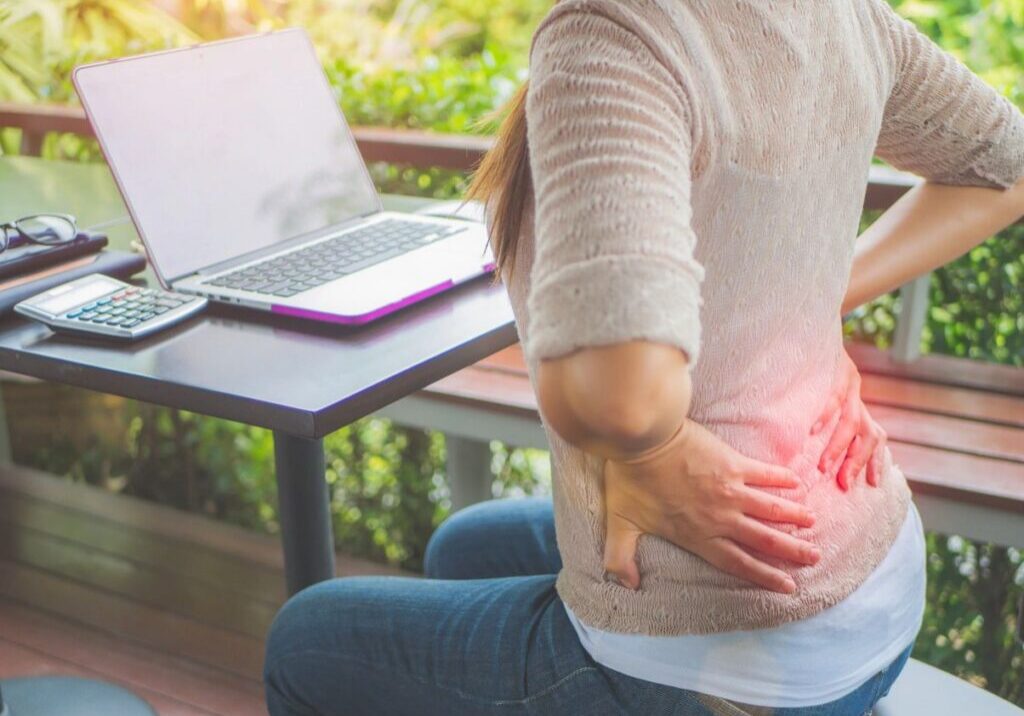 Person with back pain at outdoor desk.