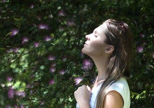 Woman enjoying nature in sunlit garden.