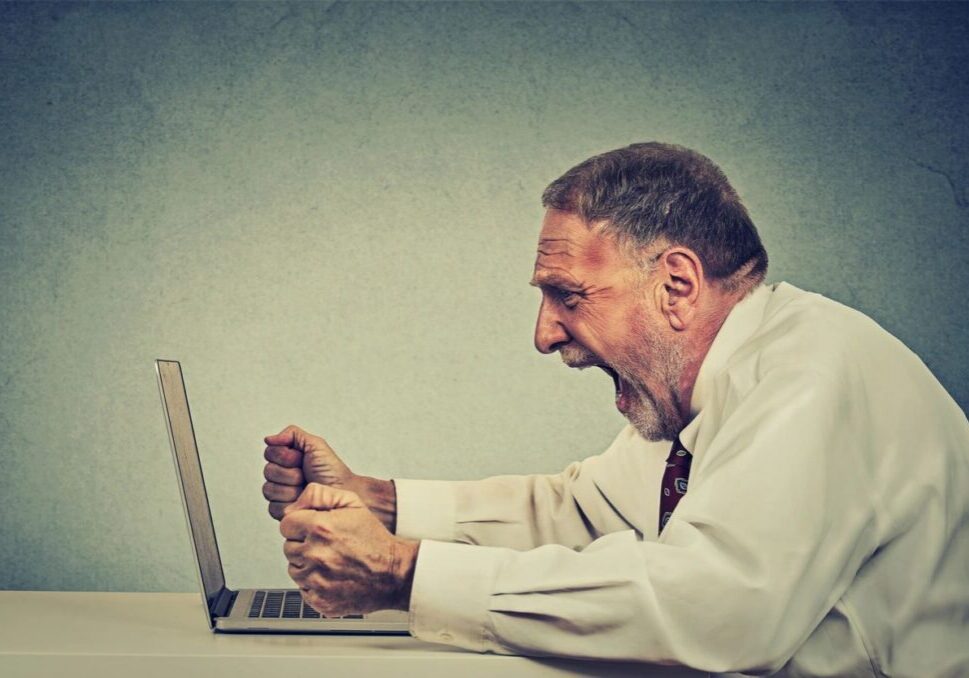 Elderly man frustrated at laptop screen.