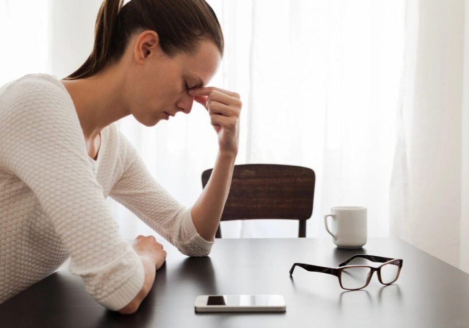 Woman stressed at table with smartphone.