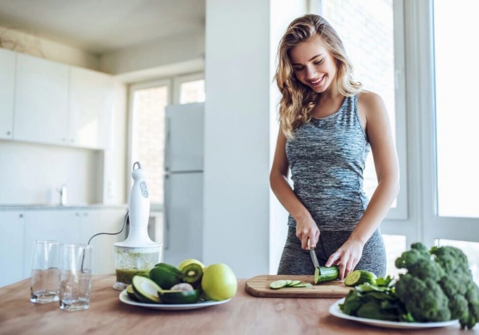 Woman slicing cucumber in modern kitchen.