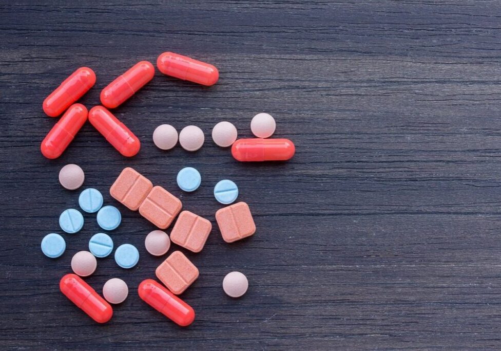 Various colorful pills on wooden surface.