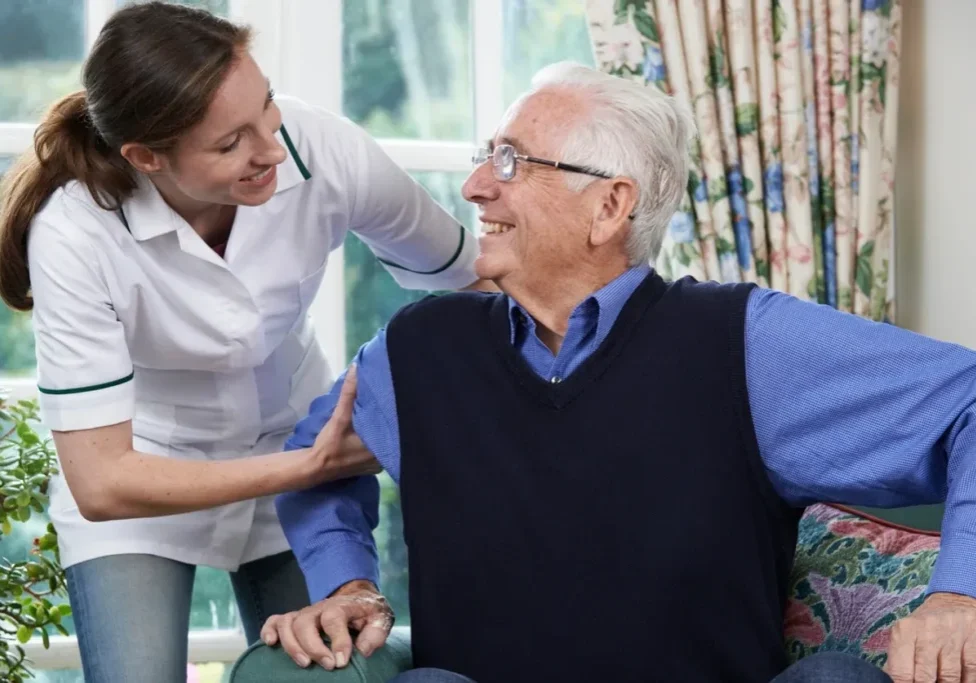 Man sitting on a couch with a nurse standing beside him