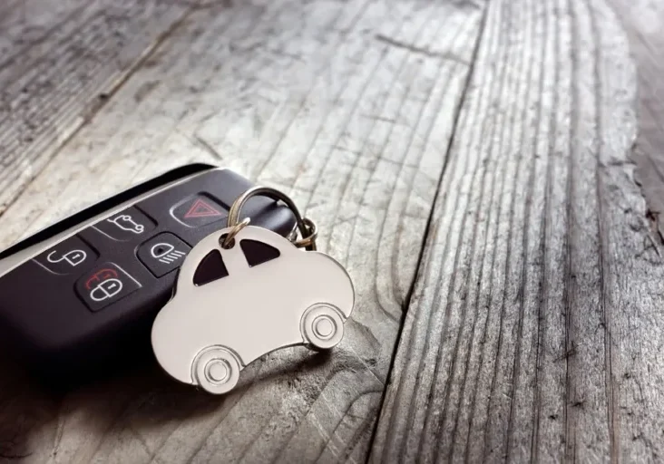Car key sitting atop a wooden table, with a keychain attached to it