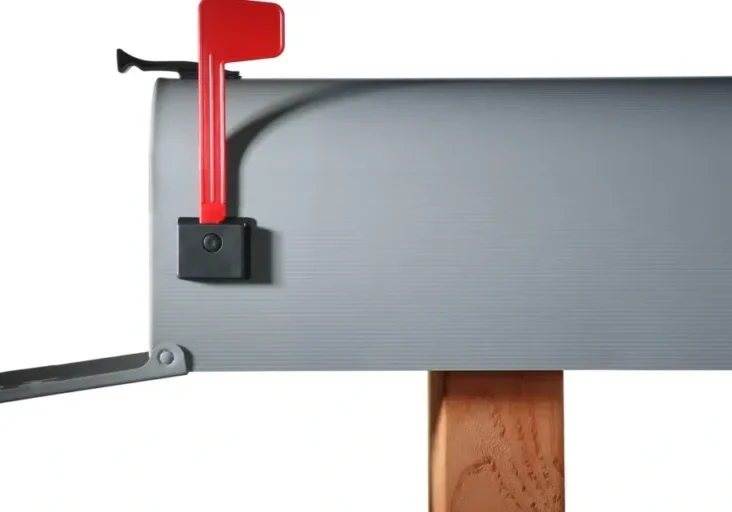 Gray mailbox with a red handle attached to a wooden post, providing a secure and reliable way to open