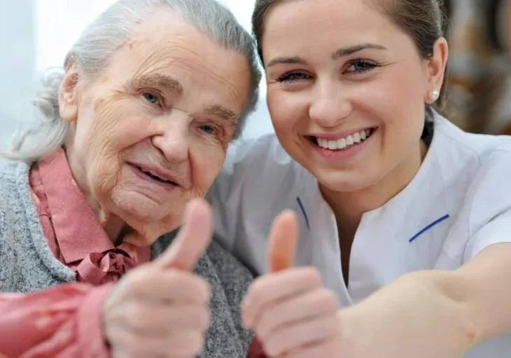 Woman giving a thumbs up to a nurse, with a blurred background
