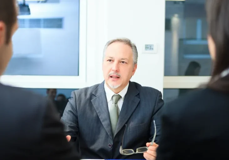 Man in a suit sitting at a table talking to two women