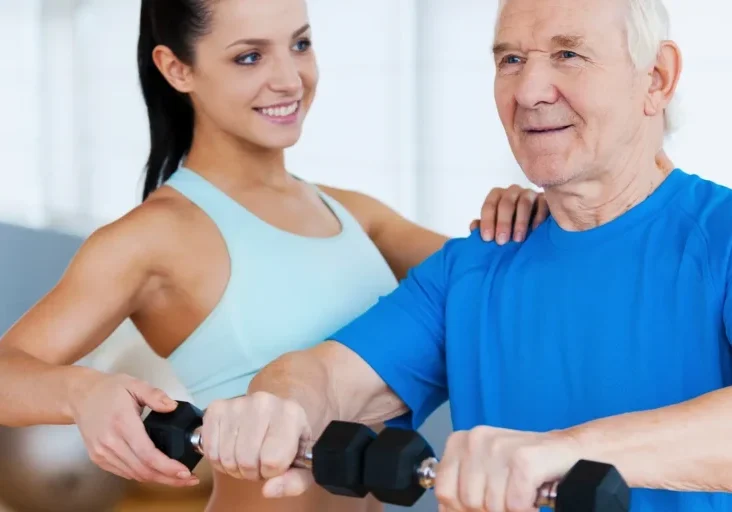 Older man and woman working out with dumbbells in a gym, with a wall in the background