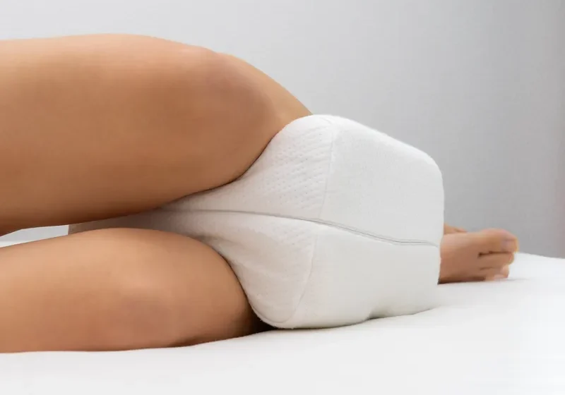 Woman laying on top of a white bed with a white pillow