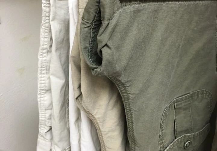 Shorts hanging on wooden hangers in closet.