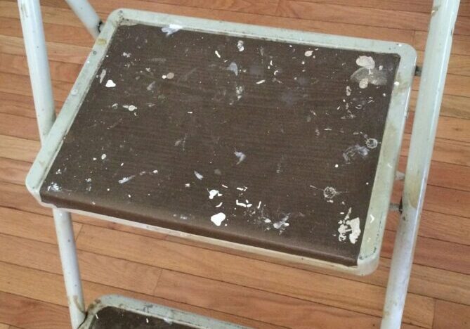 Weathered step stool on wooden floor.