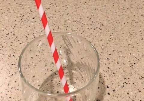 Empty glass with red striped straw.