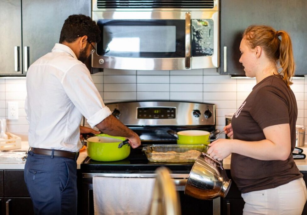 Two people cooking together in kitchen.
